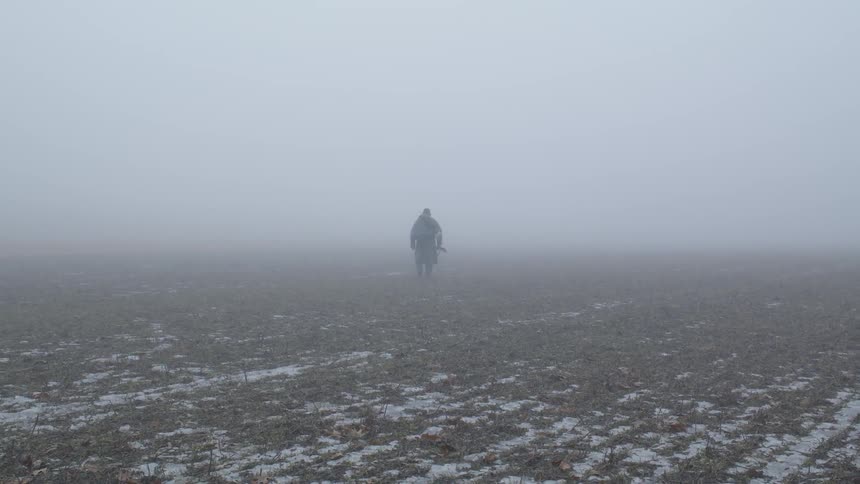 A person walks in a foggy field
