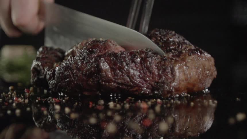 A knife cuts through a steak