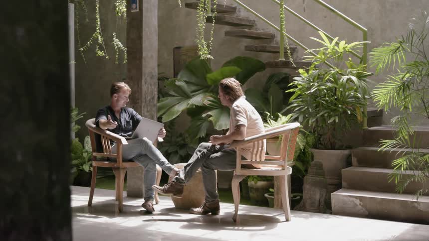 Two men sit in chairs as they talk