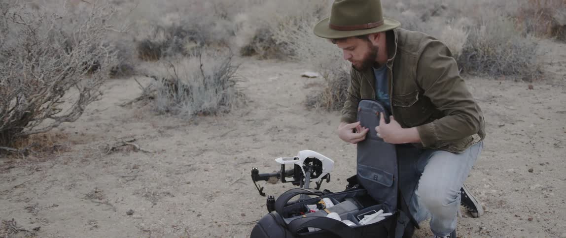 Man opens a backpack outside in the desert