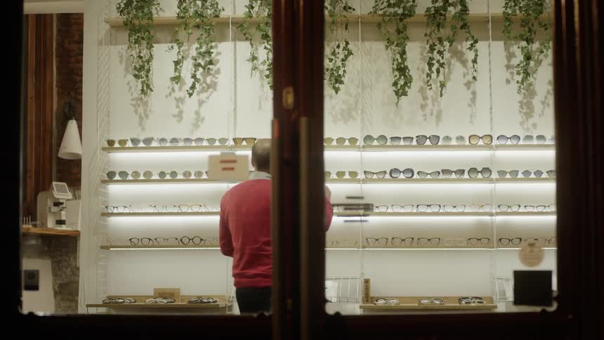 A man looks at glasses on a store shelf