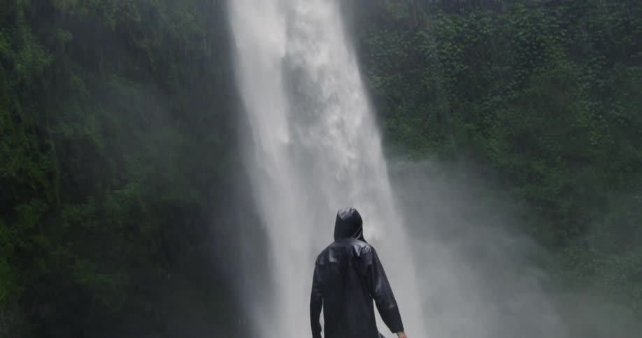 Man stands next to a waterfall