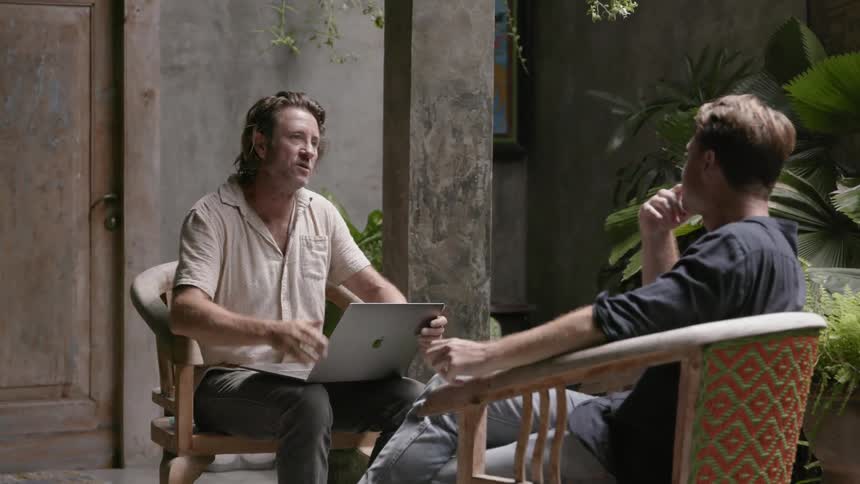 Two men talk while sitting in chairs