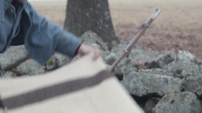 Man in a long coat puts a blanket on the ground
