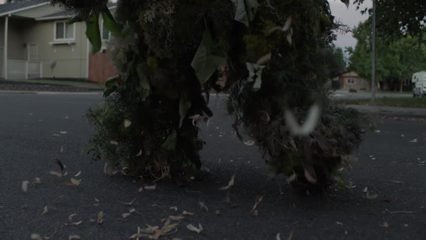 Legs of a man covered in foliage walking slowly