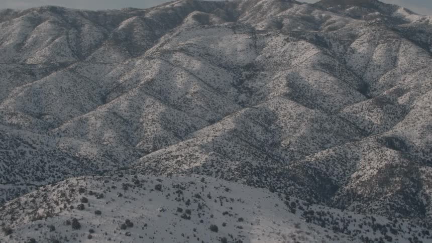 Sun sets over snow and bush covered mountains
