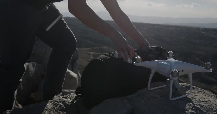 A man unzips a bag and takes out the drone controller