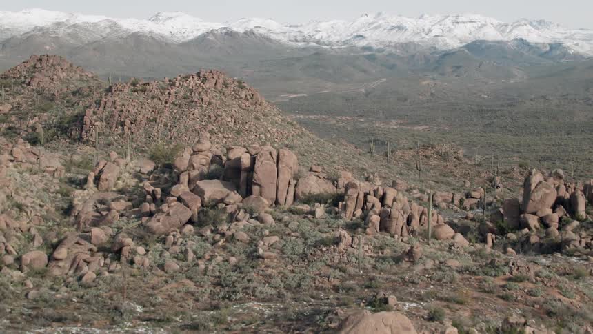Large rocks and cactus sit under the cloudy sky
