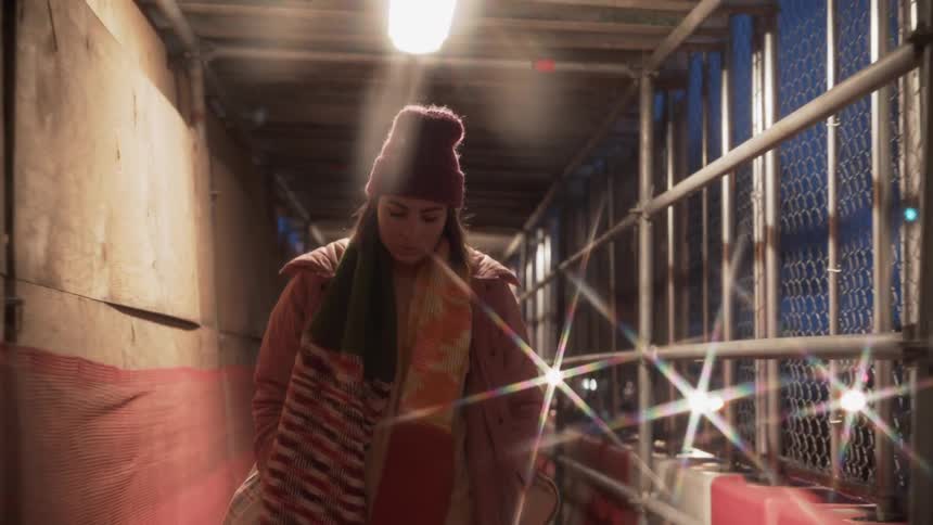 Woman walks on a city sidewalk at night