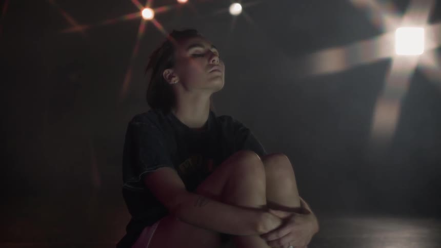 A woman rocks on the floor in the dark room