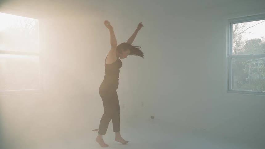 Woman dances in an empty room with sun streaming in