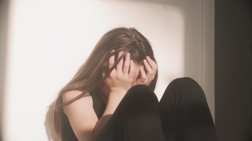 A woman sits with her head in her hands