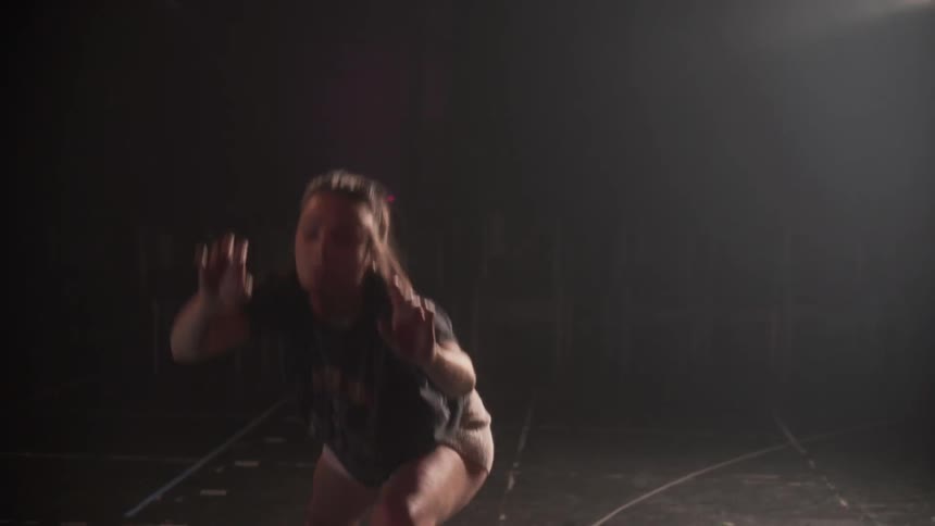 A woman dances in a studio while watching her reflection