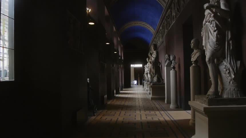 The hallway is dark and filled with statues