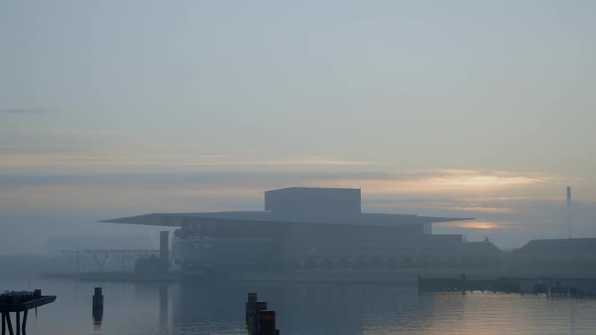 The sun sets over a lakeside building