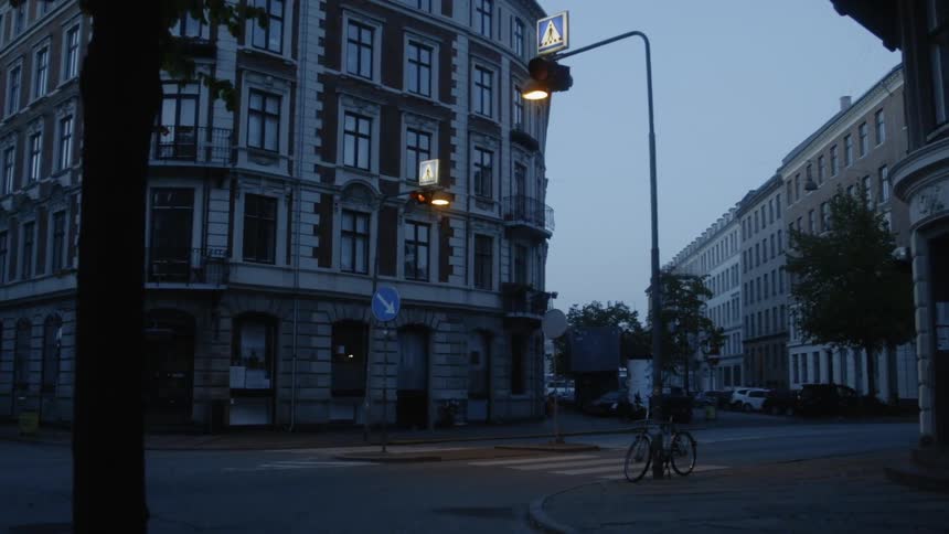 Traffic lights flash in a city at dusk