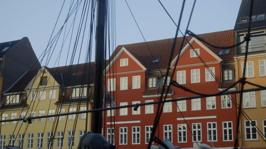 The sails on the boat are down near the homes