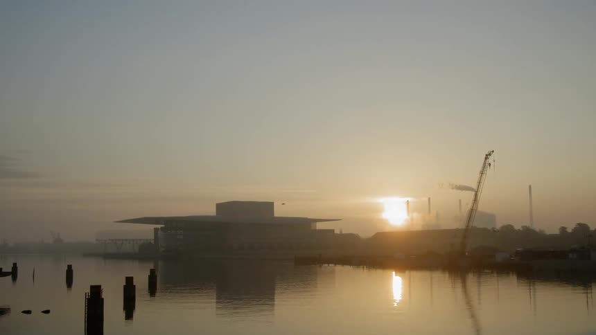 The sun sets over a lakeside building