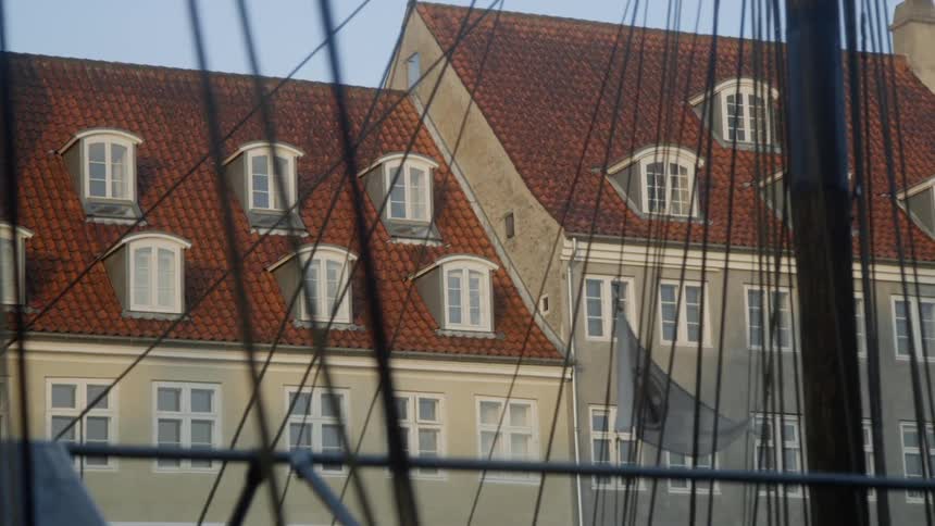 Many wires blow in the breeze near a building with a red roof