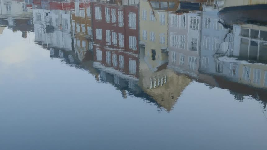 Water flows and reflects a row of buildings