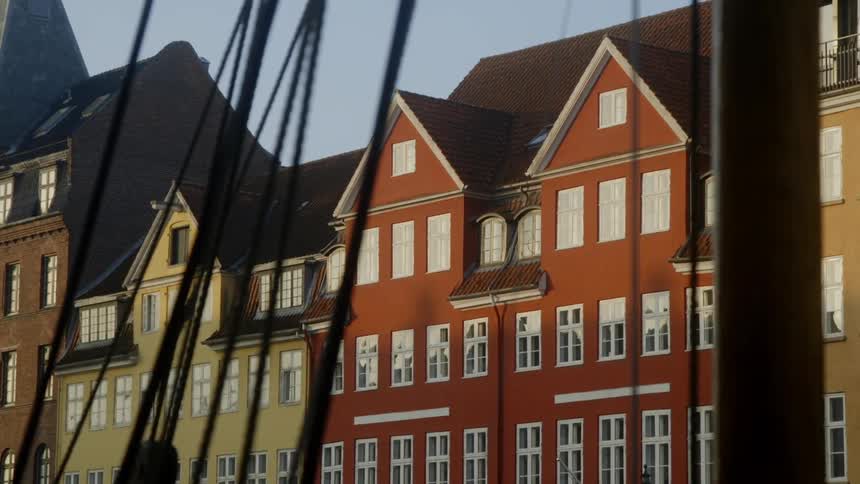 Wires hang from poles in front of a row of buildings