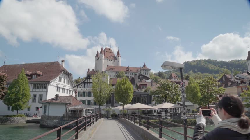 Woman takes a photo of buildings near a bridge