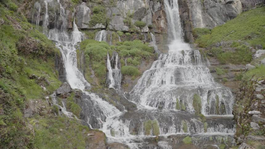 The cliff has water pouring off the edge