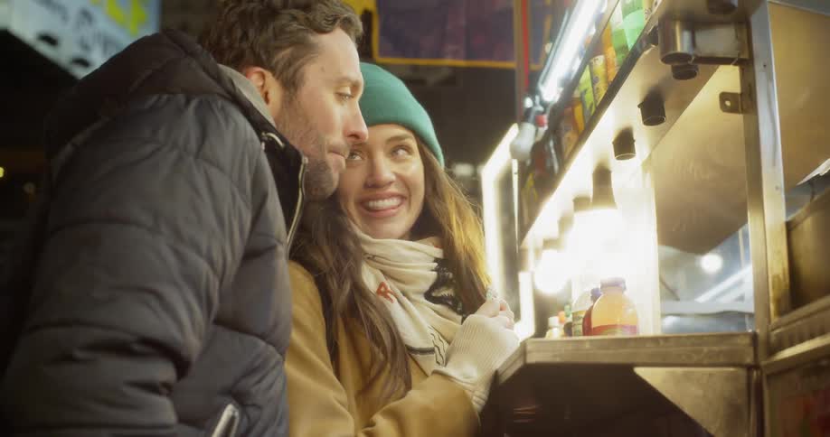 Two people talk while ordering food from a street vendor