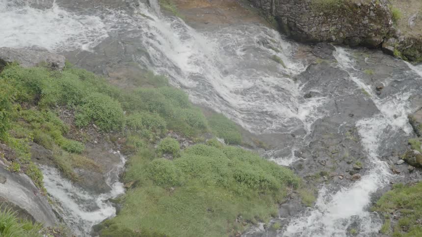 A stream is cascading over rocks as it flows downhill in daylight