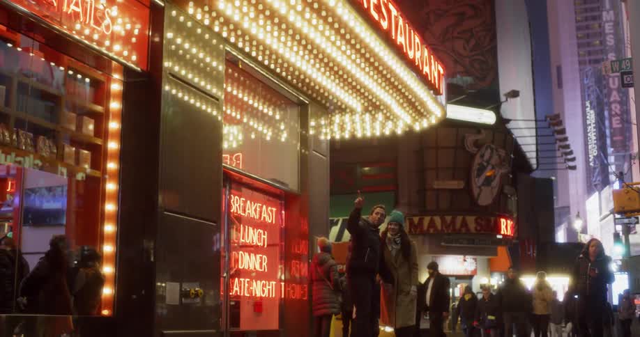 Pedestrians walk on a city sidewalk at night