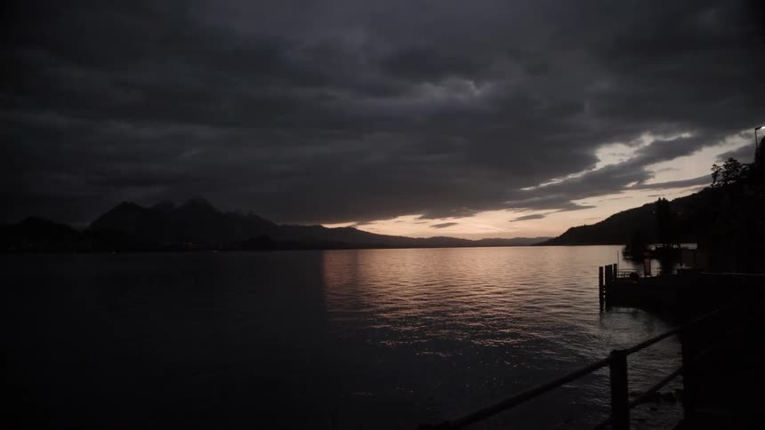 The sun sets over the ocean in a cloudy sky