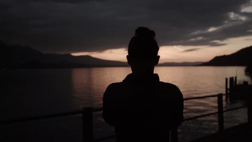 Woman looks at a lake at sunset