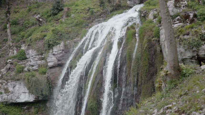 Water splashes down large rocks and moss