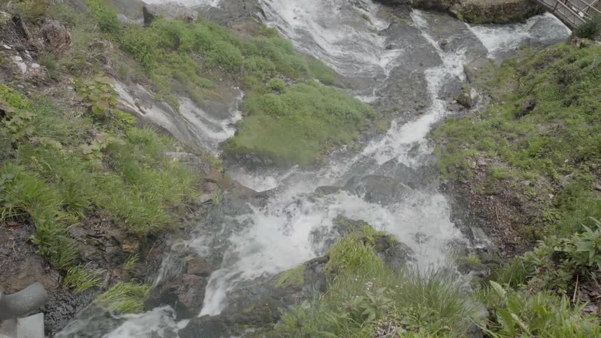 Water splashes over large rocks into a stream below
