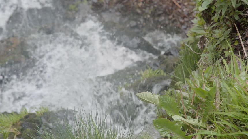 The water splashes against the rocks as it travels in the stream