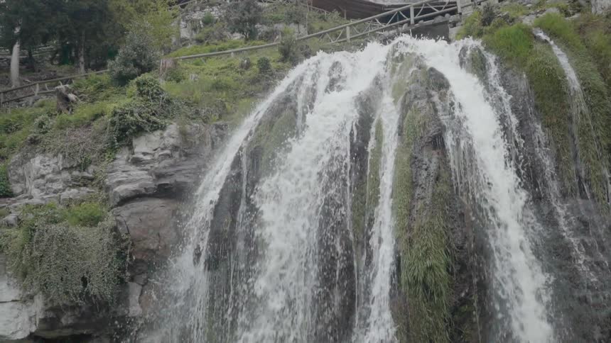 The waterfall is pouring under the railing above