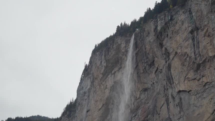The waterfall pours off the tall cliff
