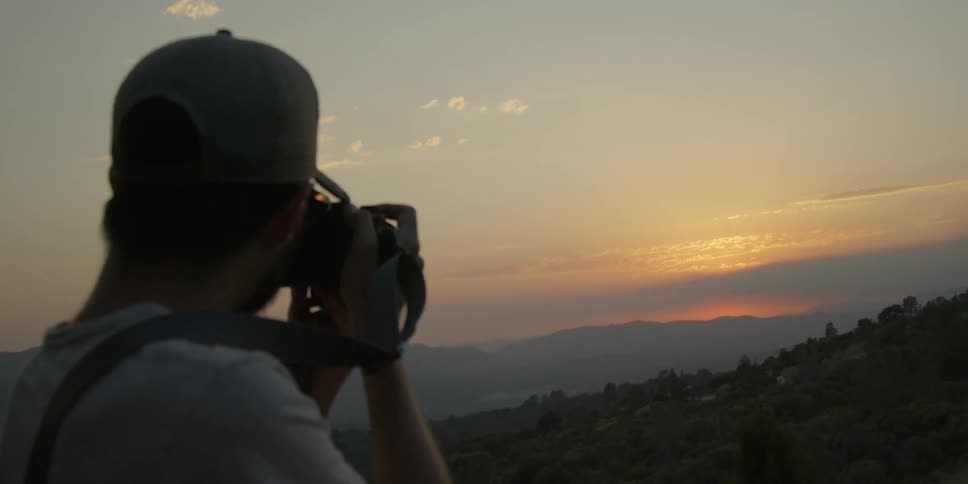 Man photographs mountains at sunset
