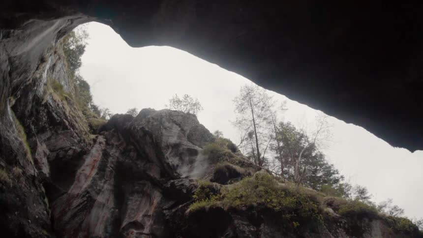 The top of the cavern is covered with grass and trees