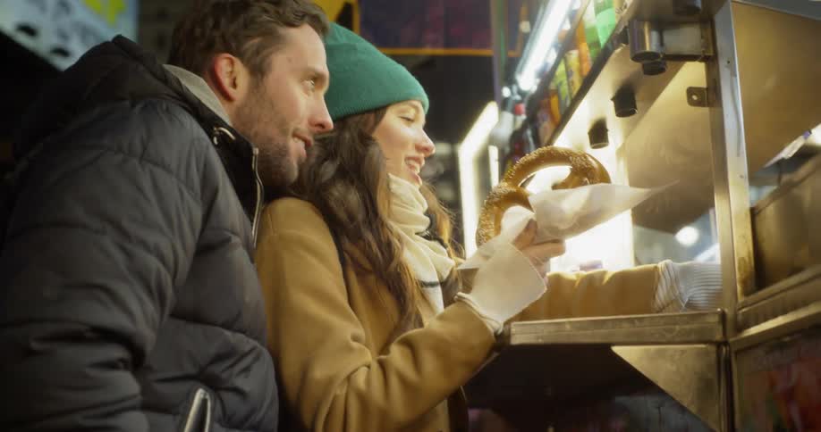 Man and woman buy a pretzel at a food cart