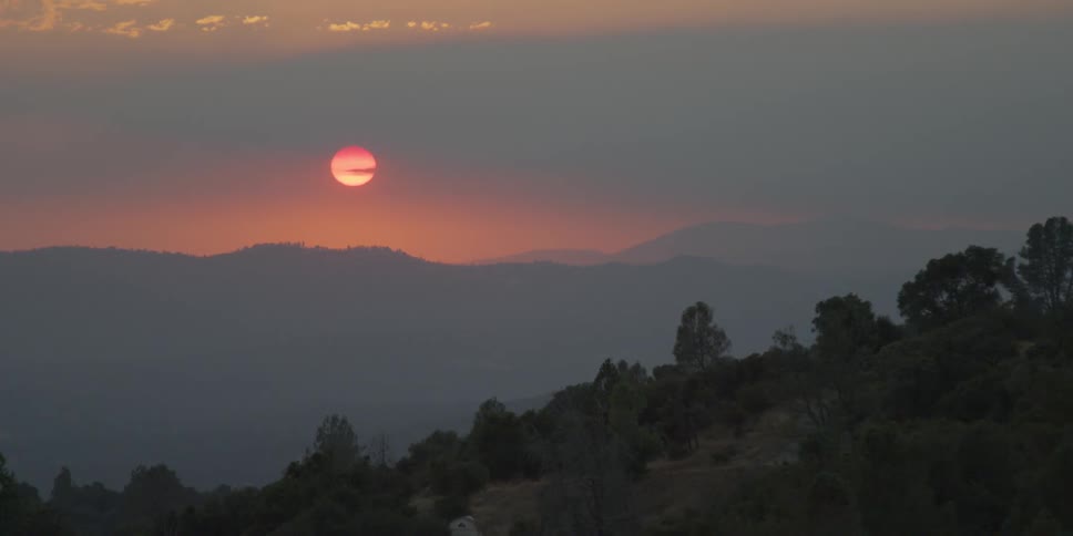 The sun turns red as it is setting behind the mountains