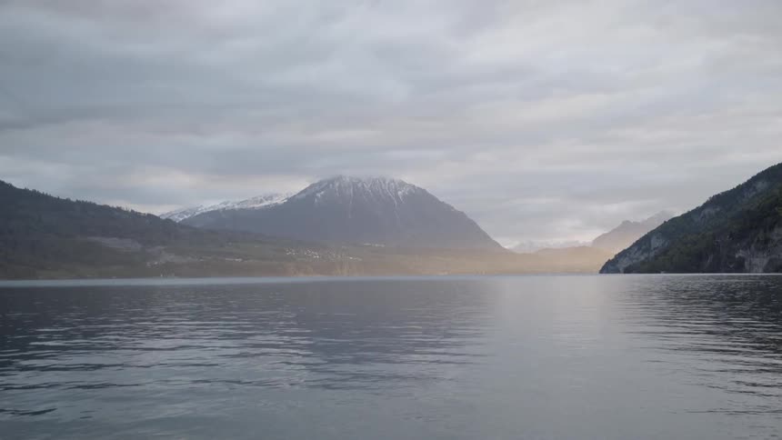 The surface of the water reflects surrounding hills and clouds
