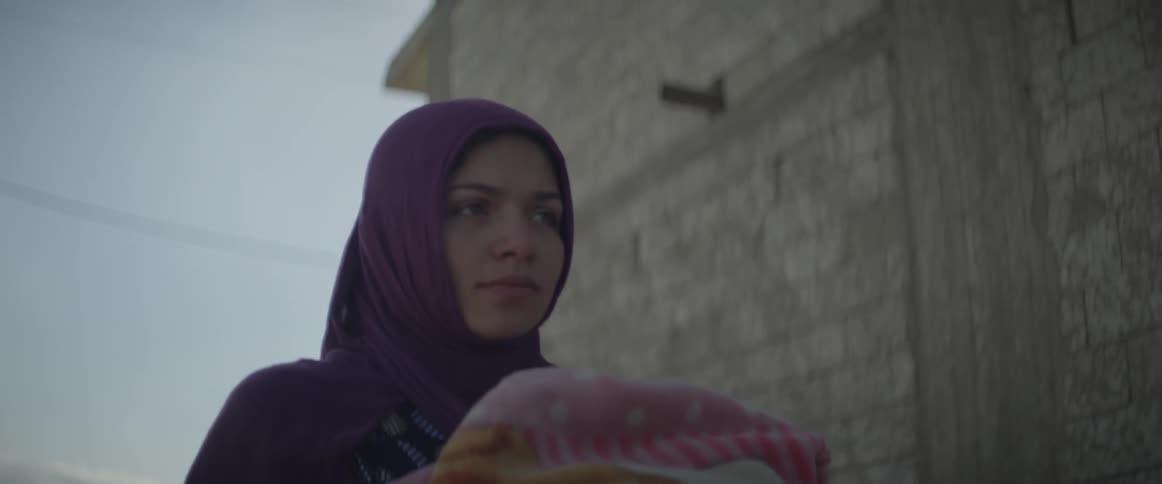 A woman walks down the street carrying a baby