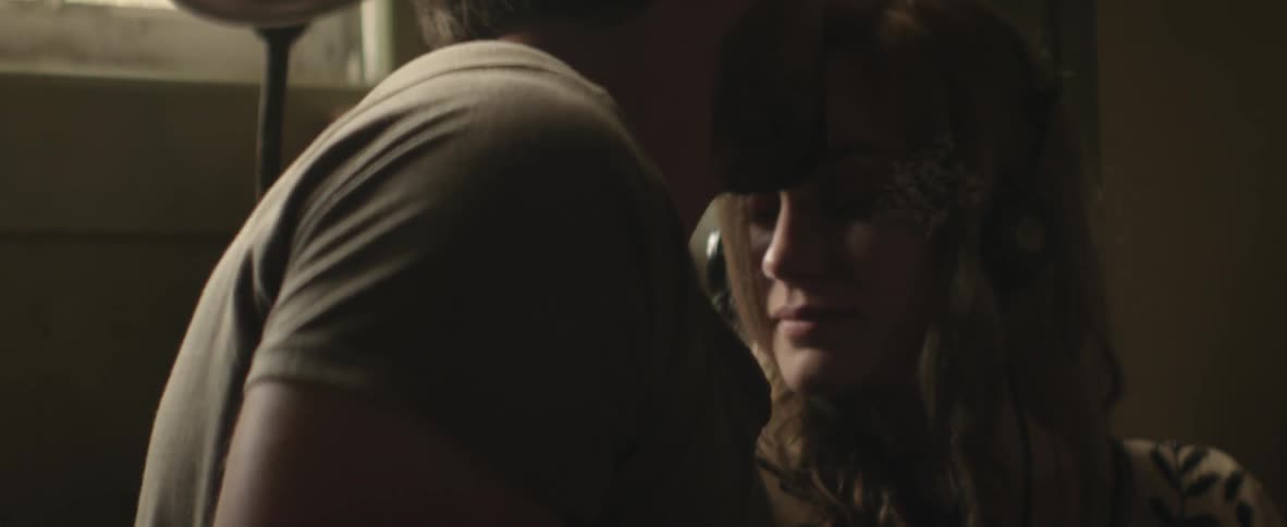 A man talks with a woman wearing headphones then kisses her forehead
