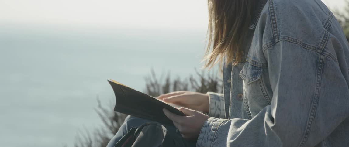 Woman writes in a notebook outside