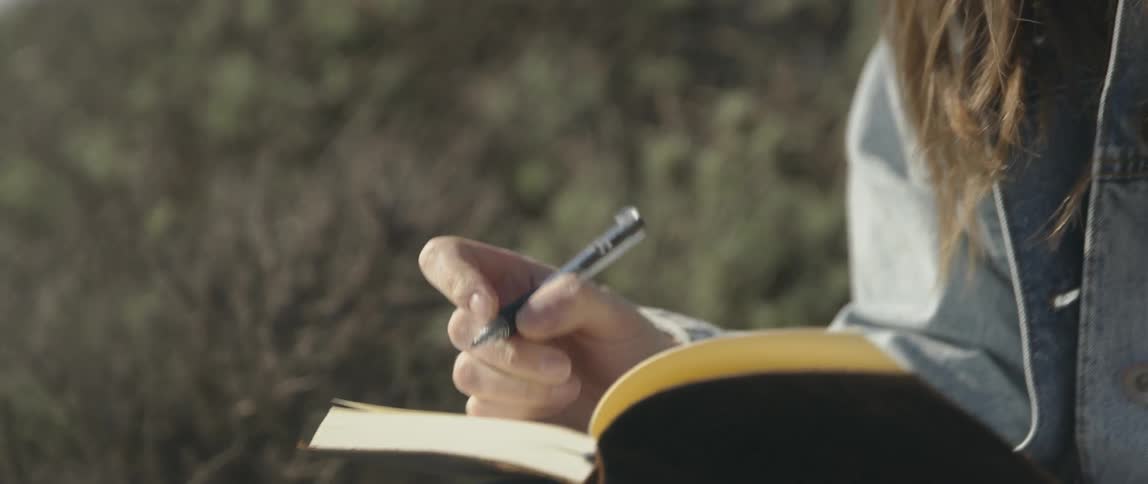 A woman is writing in her book on a windy day