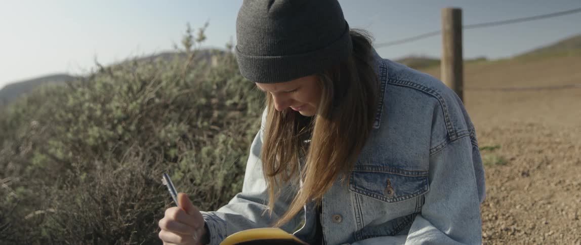 Woman writes in a notebook outside