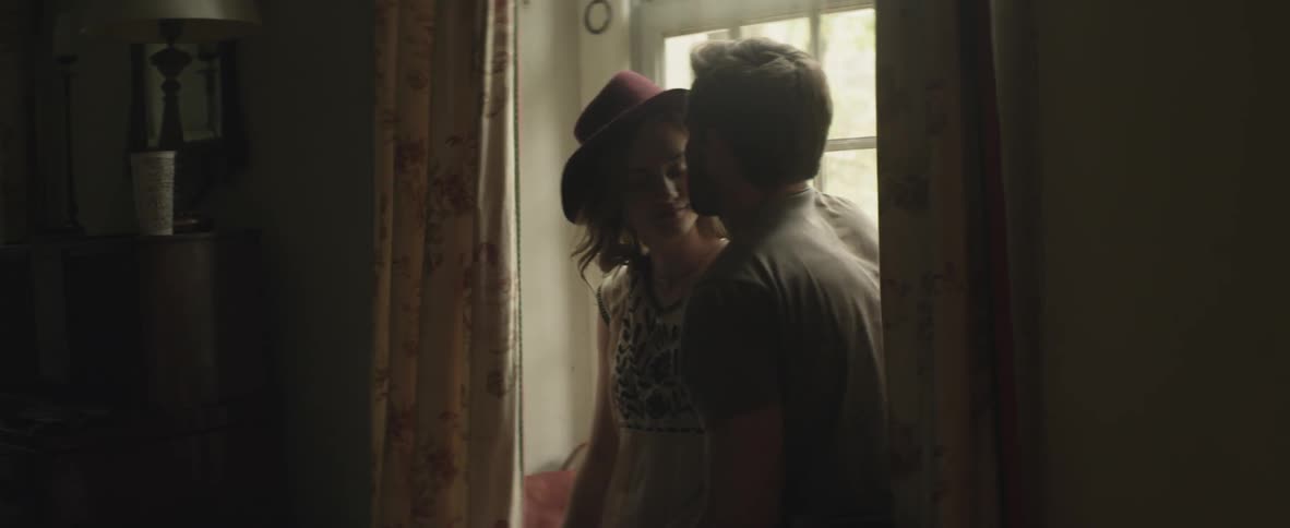 Man and woman sit by a window the man kisses her