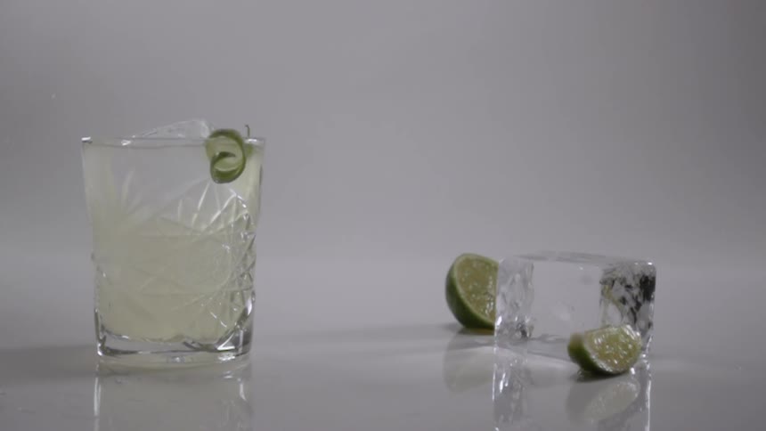 A lime peel falls into the beverage
