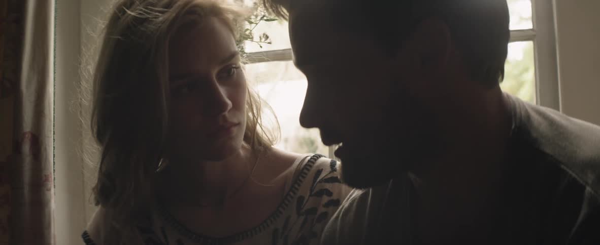 A man and woman sitting and talking in front of a window